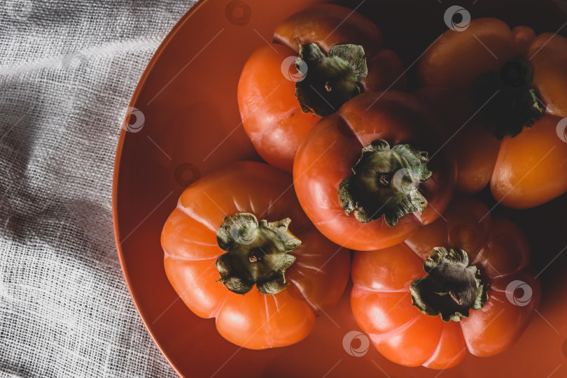 Скачать Несколько кусочков свежей хурмы на тарелке с апельсинами фотосток Ozero