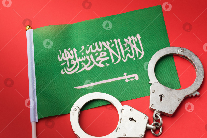 Скачать Флаг Саудовской Аравии и наручники на красном фоне, концепция преступности в стране фотосток Ozero