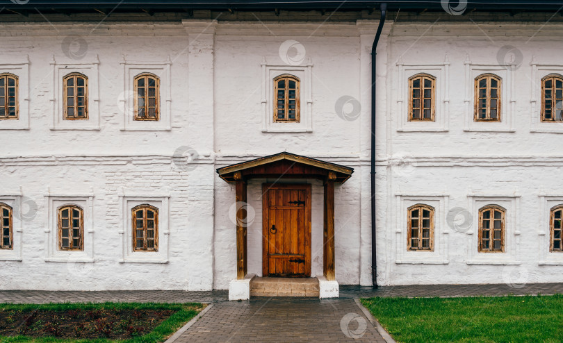 Скачать Белая стена с деревянной дверью, крыльцом и окнами. фотосток Ozero