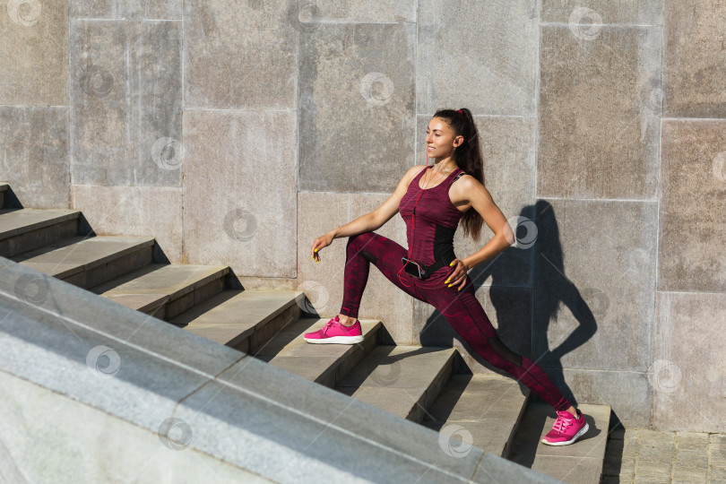 Скачать Молодая женщина занимается спортом на открытом воздухе летним солнечным утром, выполняет упражнения на растяжку. Концепция на тему здорового образа жизни фотосток Ozero