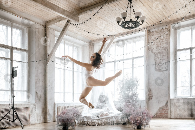 Скачать молодая балерина в легком купальнике и пуантах в просторном помещении тренируется, репетирует фотосток Ozero