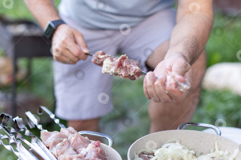 Скачать Мужчина нанизывает мясо на шампур фотосток Ozero