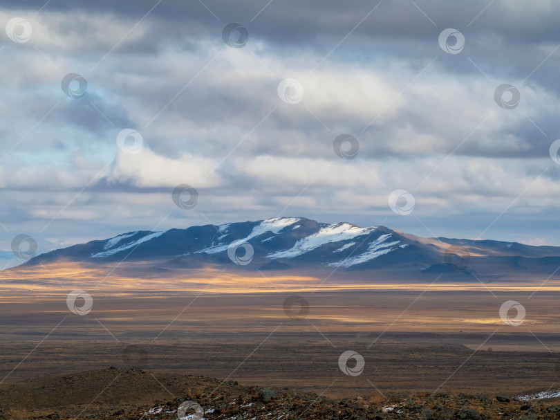 Скачать Поле с пожухлой травой, покрытые снегом горы, облачное небо. фотосток Ozero