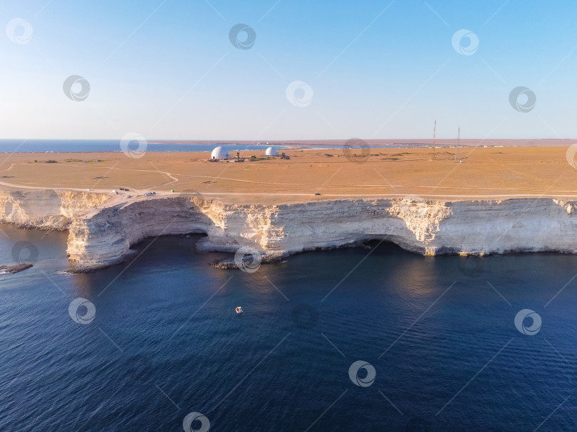 Скачать Мыс Тарханкут с бирюзовой водой на западном побережье полуострова Крым. Летний морской пейзаж, известное место для путешествий. Живописный морской пейзаж, пляж на побережье Крыма, Черное море, горы Ялты. Скалистый обрыв, уходящий в море фотосток Ozero