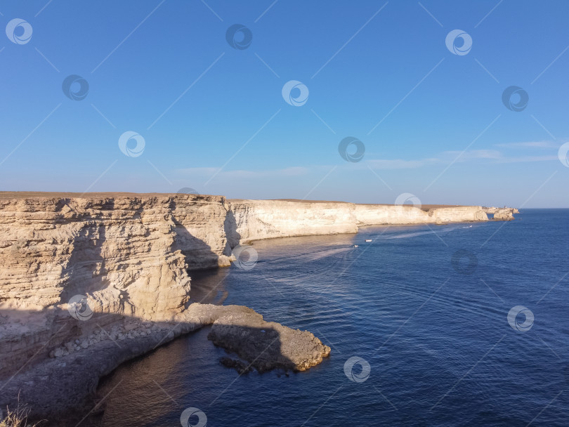 Скачать Мыс Тарханкут с бирюзовой водой на западном побережье полуострова Крым. Летний морской пейзаж, известное место для путешествий. Живописный морской пейзаж, пляж на побережье Крыма, Черное море, горы Ялты. Скалистый обрыв, уходящий в море фотосток Ozero