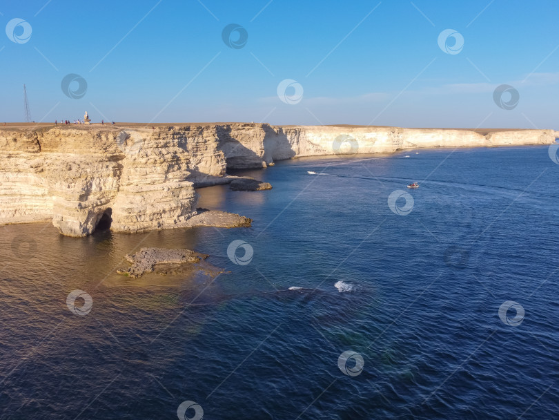 Скачать Мыс Тарханкут с бирюзовой водой на западном побережье полуострова Крым. Летний морской пейзаж, известное место для путешествий. Живописный морской пейзаж, пляж на побережье Крыма, Черное море, горы Ялты. Скалистый обрыв, уходящий в море фотосток Ozero