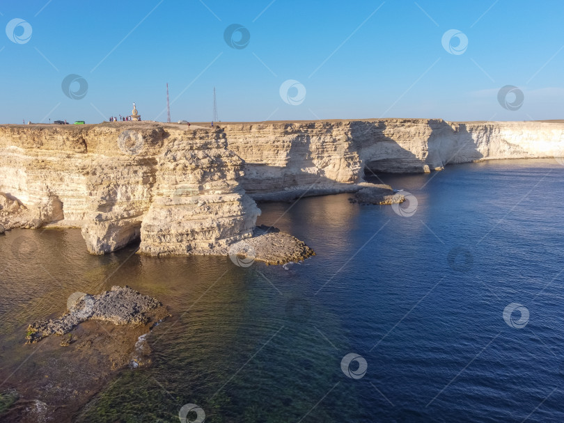 Скачать Мыс Тарханкут с бирюзовой водой на западном побережье полуострова Крым. Летний морской пейзаж, известное место для путешествий. Живописный морской пейзаж, пляж на побережье Крыма, Черное море, горы Ялты. Скалистый обрыв, уходящий в море фотосток Ozero