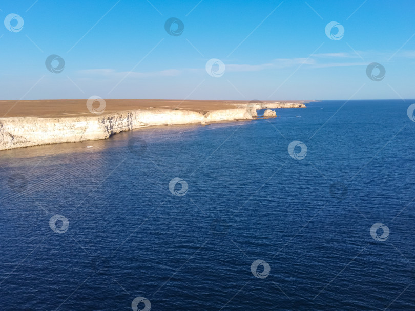 Скачать Мыс Тарханкут с бирюзовой водой на западном побережье полуострова Крым. Летний морской пейзаж, известное место для путешествий. Живописный морской пейзаж, пляж на побережье Крыма, Черное море, горы Ялты. Скалистый обрыв, уходящий в море фотосток Ozero