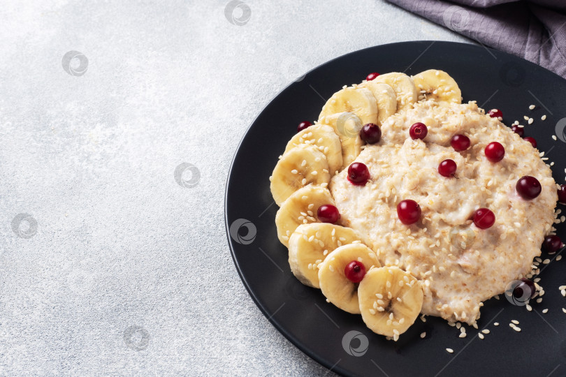 Скачать Овсяная каша на молоке с бананом, клюквой и кунжутом. Концепция здорового завтрака. Место для копирования фотосток Ozero