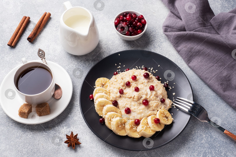 Скачать Овсяная каша на молоке с бананом, клюквой и кунжутом. Чашечка кофе - концепция здорового завтрака. фотосток Ozero