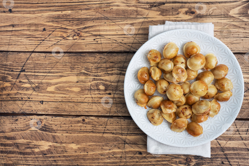 Скачать Традиционные жареные пельмени, равиоли, вареники с мясной начинкой на тарелке, русская кухня. Деревянный стол в деревенском стиле, место для копирования. фотосток Ozero