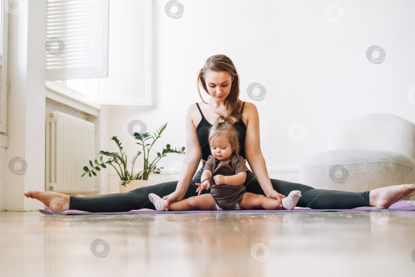Скачать Молодая женщина, подтянутая мама с маленькой девочкой, занимается фитнесом на коврике дома фотосток Ozero
