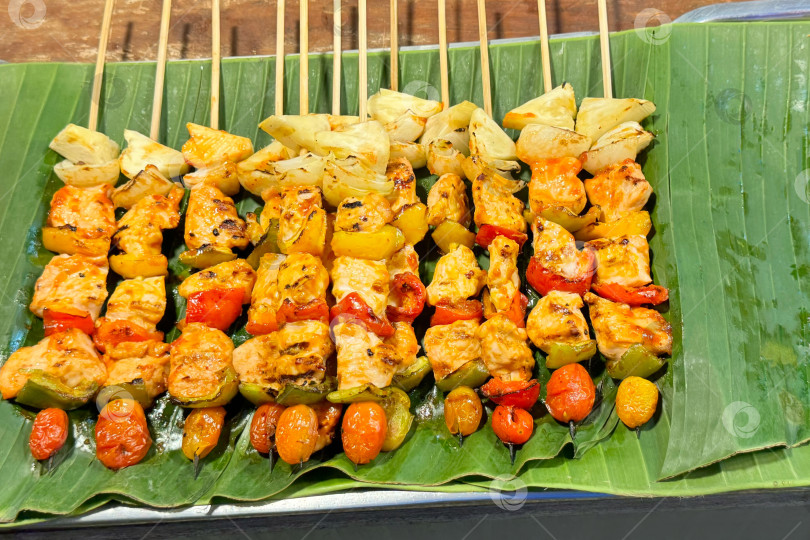 Скачать Разноцветные шашлыки-гриль на банановом листе с курицей, перцем и ананасом фотосток Ozero