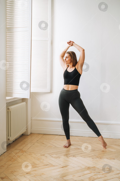Скачать Молодая стройная женщина в спортивной одежде делает упражнения по фитнесу, девушка танцует в яркой студии фотосток Ozero