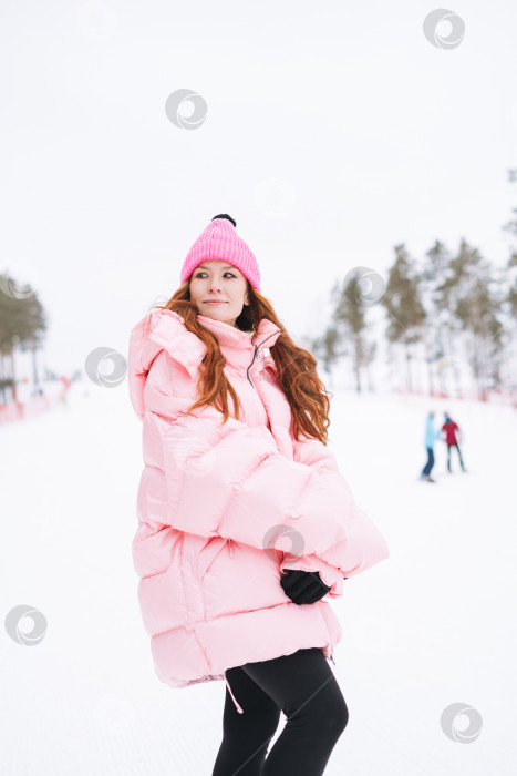 Скачать Молодая рыжеволосая женщина в розовой спортивной одежде на фоне зимнего снега фотосток Ozero