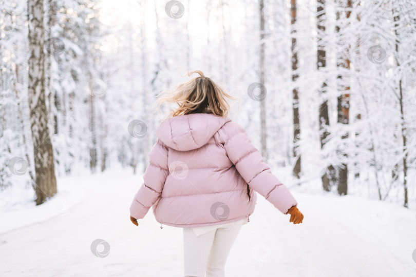 Скачать Размытая фотография молодой светловолосой женщины в зимней одежде, гуляющей по заснеженному зимнему лесу фотосток Ozero