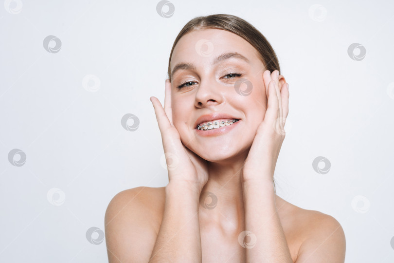 Скачать Красивый портрет забавной молодой девушки со свежей кожей, подростка с брекетами на зубах на белом фоне изолированно фотосток Ozero