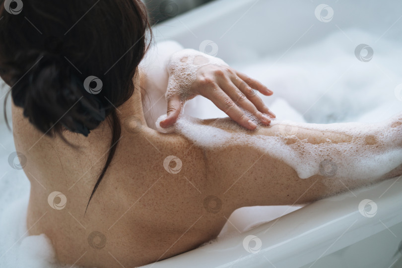 Скачать Обрезанная фотография любящей себя взрослой брюнетки, принимающей ванну с пеной дома фотосток Ozero