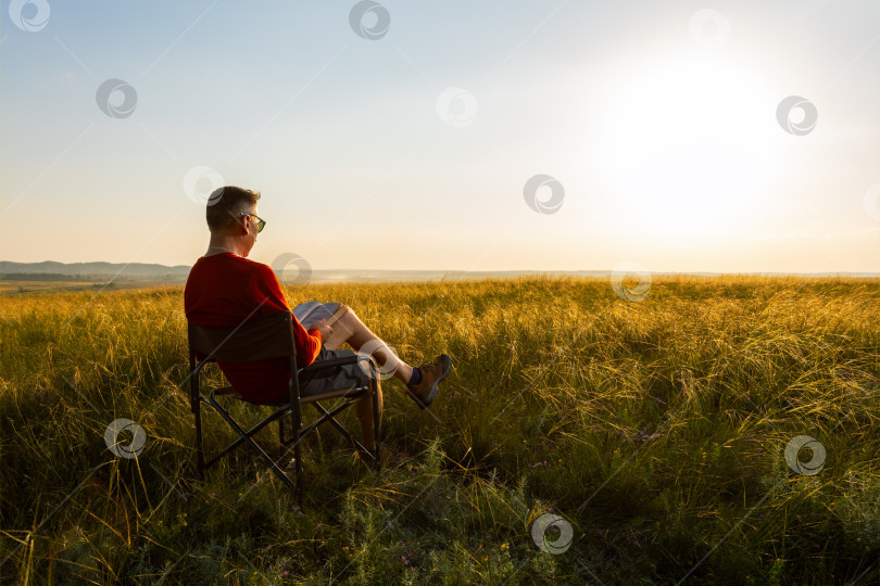 Скачать мужчина сидит на уличном стуле на природе и наслаждается чтением книги. фотосток Ozero