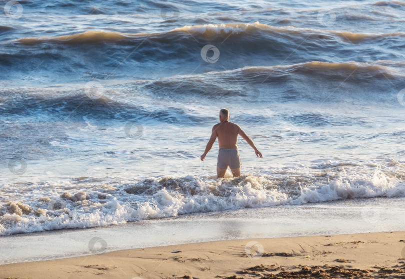 Скачать Человек входит в море с большой волной фотосток Ozero