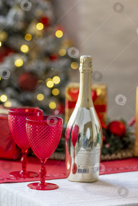 Скачать Бутылки с шампанским и бокалы на столе на фоне рождественских украшений фотосток Ozero
