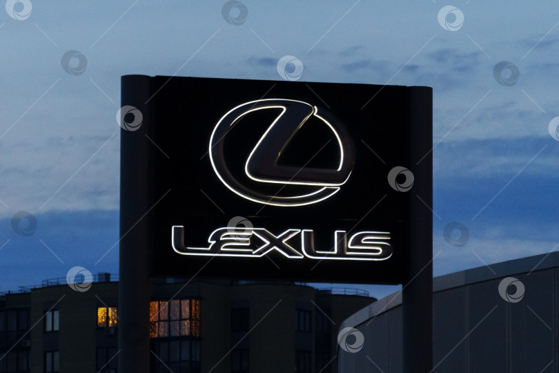 Скачать Тюмень, Россия - 18 марта 2024 года: Вывеска с логотипом Lexus на стене здания, указывающая на дилерский или сервисный центр марки автомобилей класса люкс. фотосток Ozero