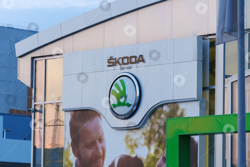 Скачать Тюмень, Россия - 18 марта 2024 года: Логотип Skoda размещен на видном месте перед коммерческим зданием в разделе Skoda vehicles. фотосток Ozero