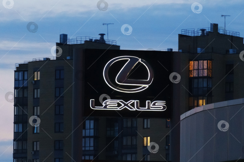 Скачать Тюмень, Россия - 18 марта 2024 года: Вывеска с логотипом автосалона Lexus стоит на видном месте перед зданием. фотосток Ozero