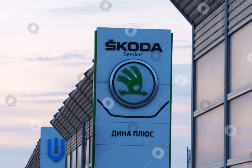 Скачать Тюмень, Россия - 18 марта 2024 года: Логотип Skoda размещен на видном месте перед коммерческим зданием в разделе Skoda vehicles. фотосток Ozero