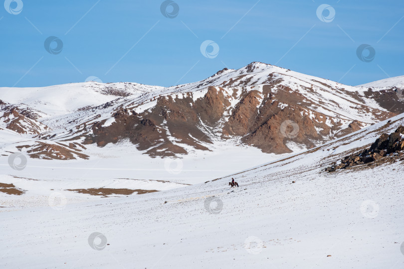 Скачать Всадник на белом заснеженном горном склоне. фотосток Ozero