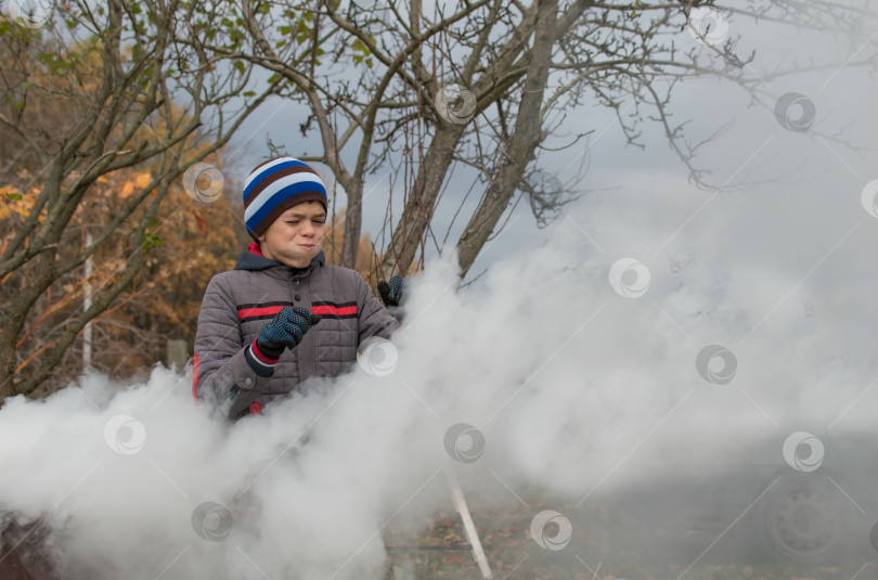 Скачать Мальчик-подросток сжигает осенние листья на загородном участке фотосток Ozero