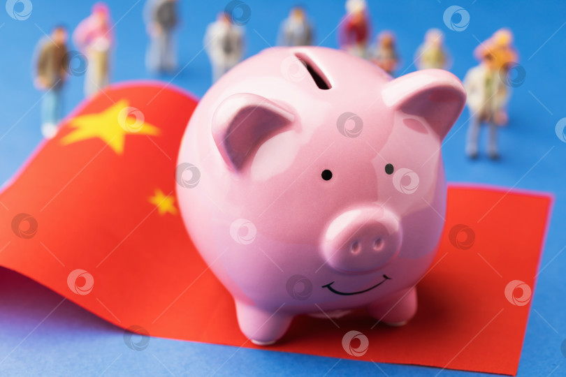 Скачать Копилка, китайский флаг и пластмассовые игрушечные человечки на цветном фоне, концепт на тему дохода в Китае фотосток Ozero
