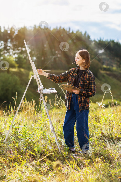 Скачать Молодая женщина-художница рисует картину в парке летним солнечным вечером фотосток Ozero