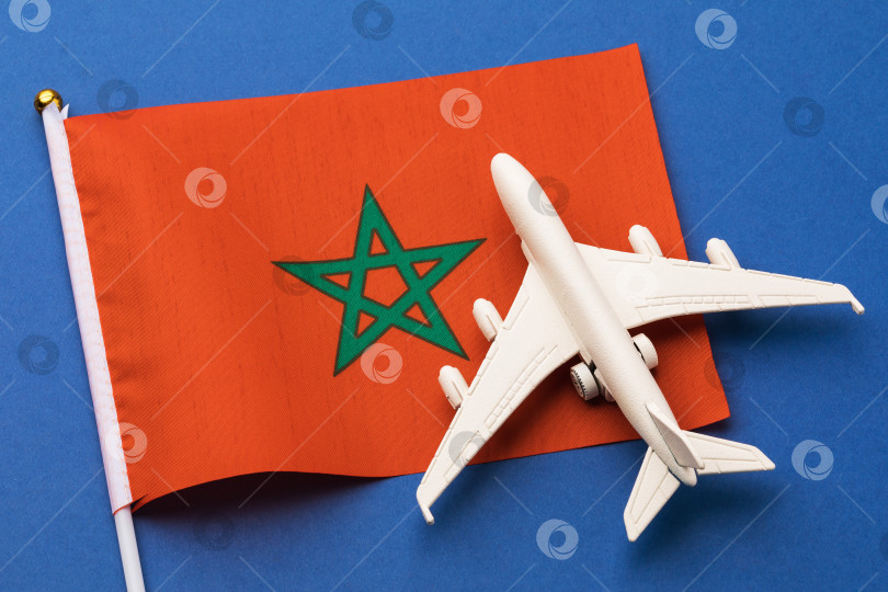 Скачать Марокканский флаг и игрушечный самолетик на синем фоне, концепция полета в Марокко, вид сверху фотосток Ozero
