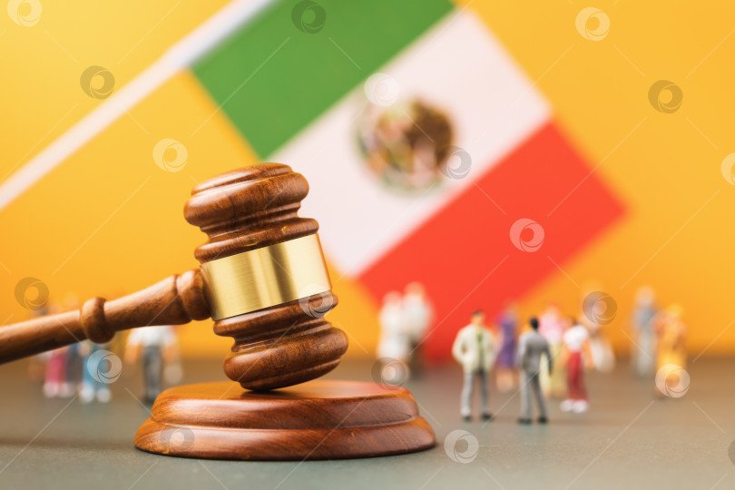 Скачать Деревянный судейский молоток, флаг и пластиковые игрушечные человечки на желтом фоне, концепция судебного разбирательства в мексиканском обществе фотосток Ozero