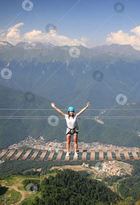 Скачать Счастливая девушка-туристка стоит в центре подвесного моста и счастливо улыбается. фотосток Ozero