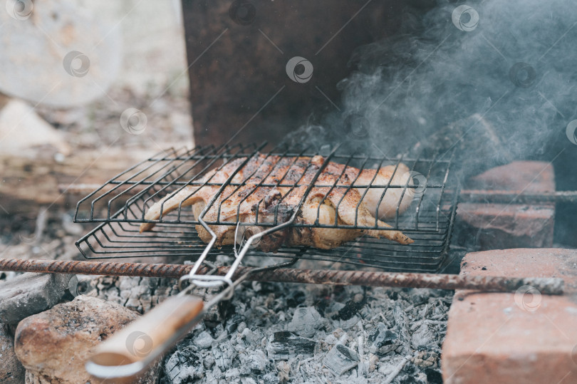 Скачать блюда из куриного мяса жарят на гриле на тлеющих углях или тлеющих углях от костра на земле летним или осенним днем. барбекю в походных условиях. выживание в сельской местности и дикая деревенская жизнь фотосток Ozero