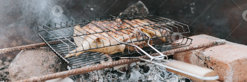 Скачать блюда из куриного мяса жарят на гриле на тлеющих углях или тлеющих угольках от костра на земле летним или осенним днем. барбекю в походных условиях. выживание в сельской местности и дикая деревенская жизнь фотосток Ozero