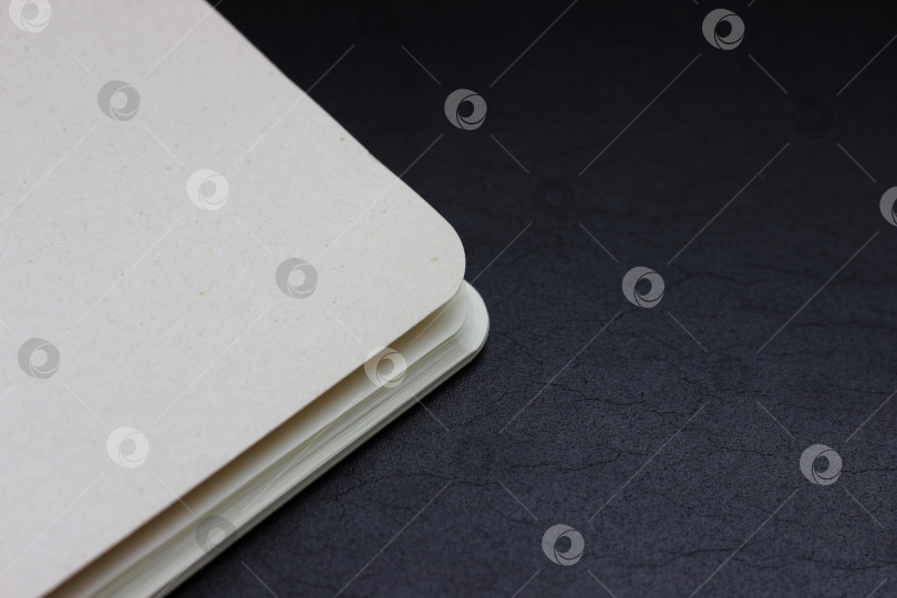 Скачать Белый закрытый уголок блокнота, лежащий на темном фоне, горизонтальная фотография фотосток Ozero