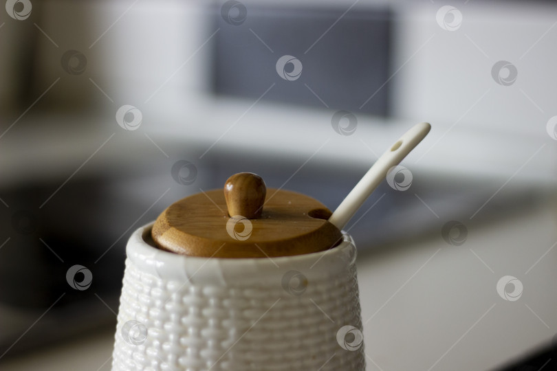 Скачать Белая текстурированная сахарница с ложкой и коричневой деревянной крышкой, горизонтальное фото фотосток Ozero