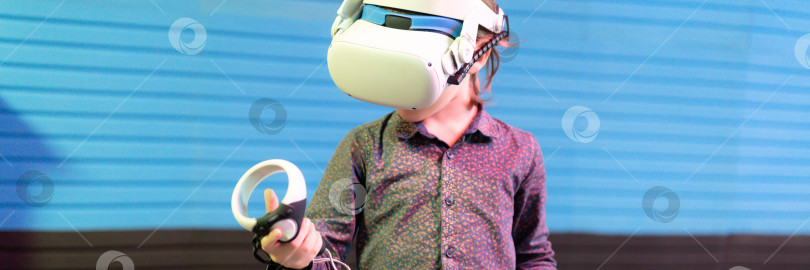 Скачать vr-игра и виртуальная реальность. малыш мальчик геймер шести лет весело играет на футуристическом симуляторе видеосъемки или исследует учебную игру в 3d очках и джойстиках в виртуальной комнате с технологией фотосток Ozero