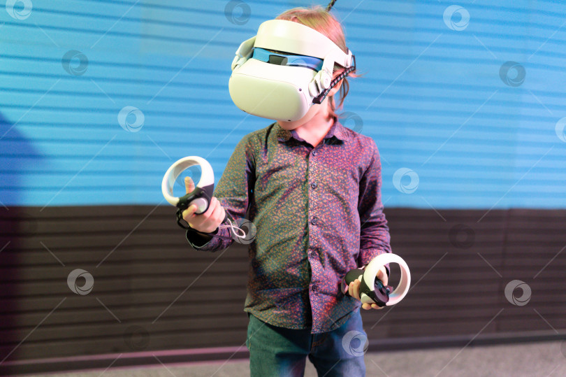 Скачать vr-игра и виртуальная реальность. малыш мальчик геймер шести лет весело играет на футуристическом симуляторе видеосъемки или исследует учебную игру в 3d очках и джойстиках в виртуальной комнате с технологией фотосток Ozero