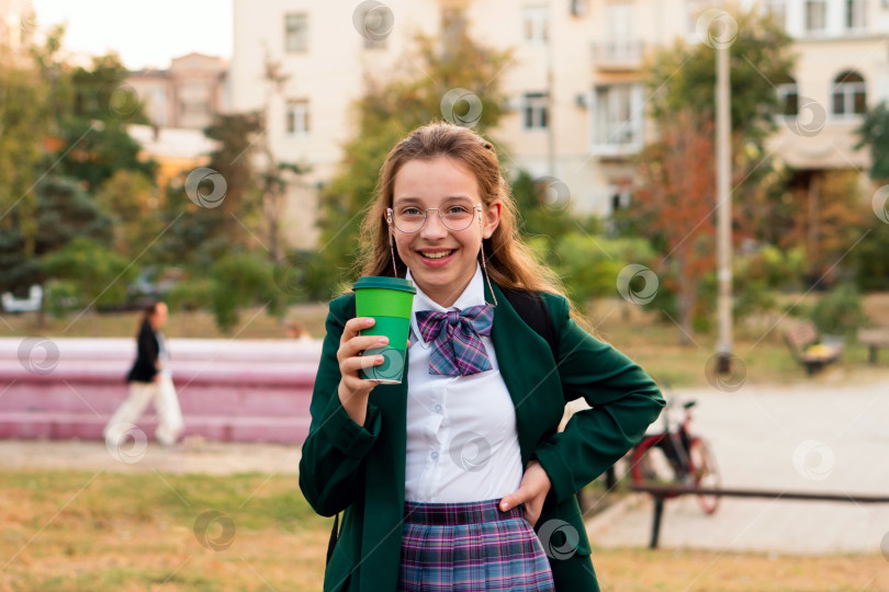 Скачать Молодая девушка в зеленом блейзере, держащая зеленую чашку на открытом воздухе фотосток Ozero