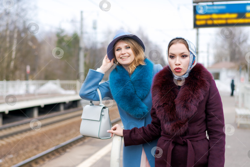 Скачать Две женщины в меховых шубах и шляпках стоят на железнодорожном вокзале фотосток Ozero