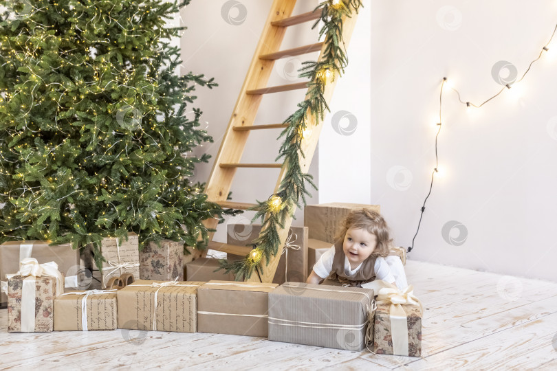 Скачать Маленькая девочка у рождественской елки с коробками подарков. Распаковка подарков, эмоции,детство фотосток Ozero