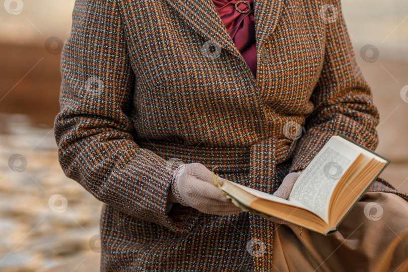 Скачать Брюнетка в винтажной одежде и шляпе с книгой в руках сидит на скамейке в осеннем парке. Ретро-стиль фотосток Ozero