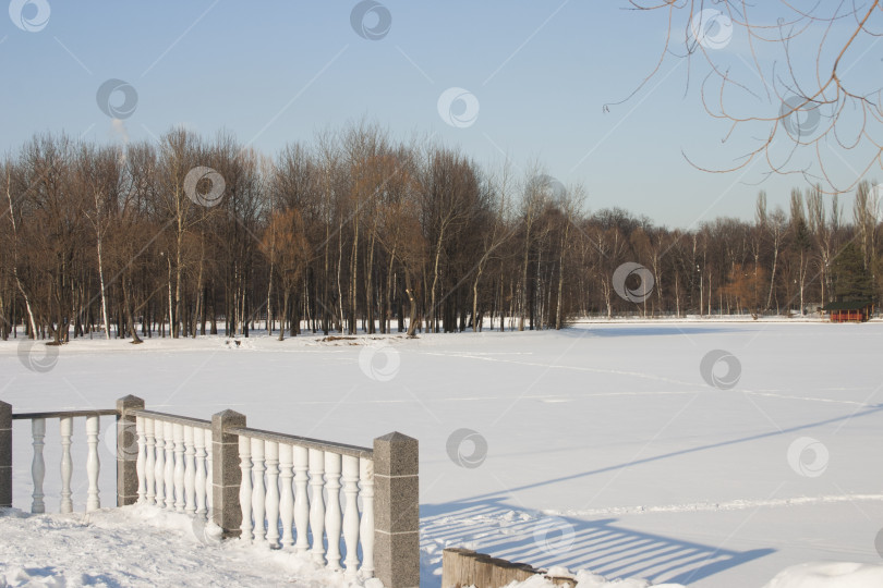 Скачать Зимний пейзаж с замерзшим озером и забором в парке. фотосток Ozero