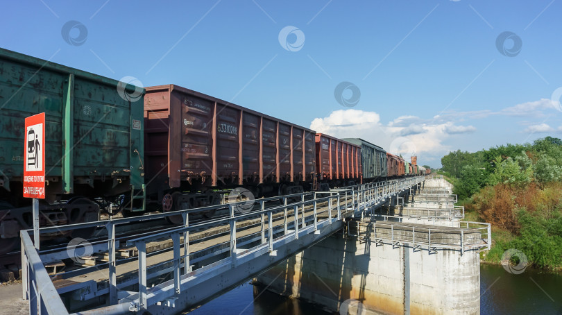 Скачать Вагоны грузового поезда на мосту. По мосту проезжает грузовой поезд. фотосток Ozero