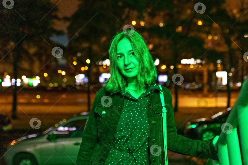 Скачать Портрет молодой женщины в ночном городе в неоново-зеленом цвете летним вечером. Городские огни фотосток Ozero