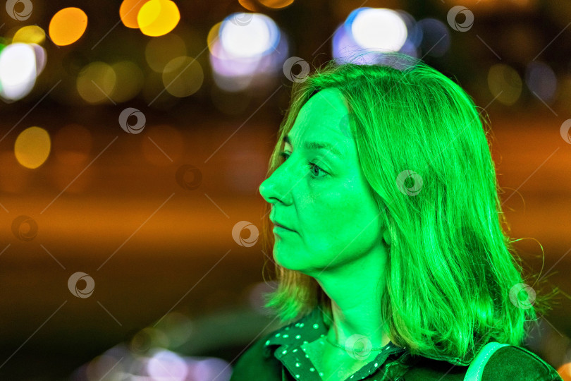 Скачать Портрет молодой женщины в ночном городе в неоново-зеленом цвете летним вечером. Городские огни фотосток Ozero